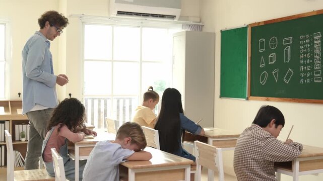 Skilled teacher walking at classroom while looking at student homework. Professional instructor checking smart children notebook while student doing test or working on homework at classroom. Pedagogy.