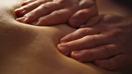 Close-up of hands massaging a person's back, highlighting relaxation and wellness in a serene spa setting. The image conveys calm and rejuvenation, ideal for self-care and beauty treatments.