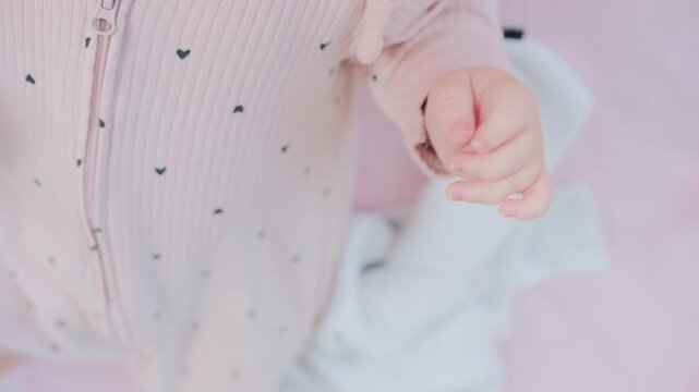 Close up of baby's tiny hand reaching out gently in soft pastel tones