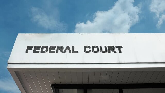 Federal Court word sign prominently displayed on the official government building facade beneath a clear blue sky, signifying the central judicial branch institution handling national legal matters.