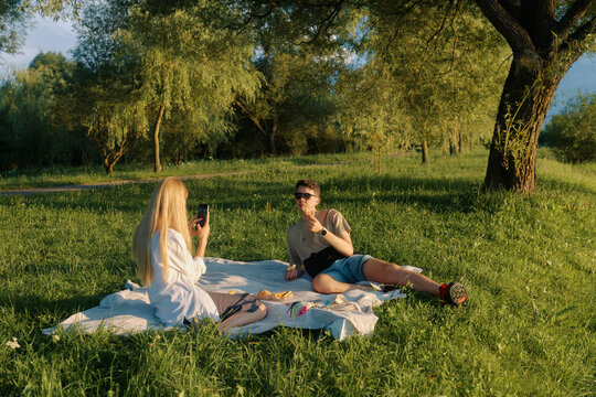 Enjoying a relaxed picnic by a tranquil pond on a sunny afternoon with friends