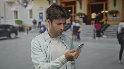 Man typing on smartphone with hands on screen on street in front of building steps, checking messages; urban connection focus. - Powered by Adobe