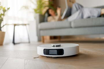 White robotic vacuum cleaner on wooden floor