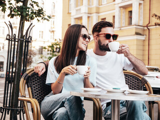 Smiling beautiful woman and her handsome boyfriend. Happy cheerful family. Couple drinking coffee in restaurant. They drinking tea at cafe in street. Holding cup. Enjoying their date