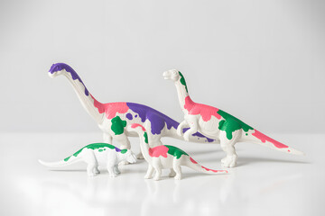 Colorful dinosaur toys standing together on a white background