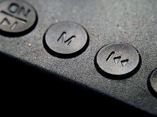 Buttons are presented in a dimly lit environment, casting shadows over its textured surface area.