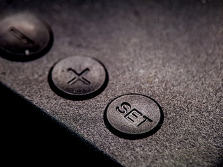 A low angle view of dark grey buttons, one with an 'X' and one with the word 'SET'.