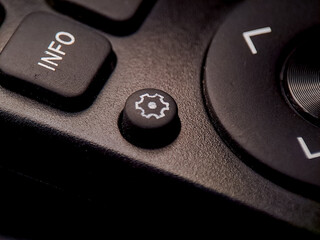 Black remote control button with a white gear icon to access settings and adjust parameters.