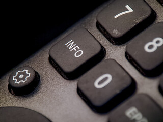 Macro shot depicts the gray remote control featuring number buttons and an information button.