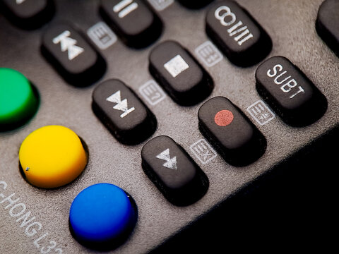 Angled view of a control panel featuring playback, record, and subtitle buttons on a gray surface.