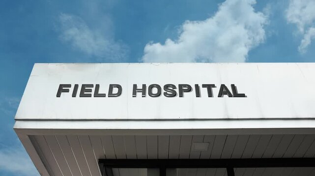 Field Hospital word sign clearly displayed on the temporary or modular building facade beneath a clear blue sky, signifying a mobile or non-permanent medical facility for immediate care.