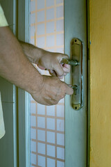 Close-up of a hand inserting a key into an old rusty door lock, symbolizing security, access, and safety concepts, in portrait