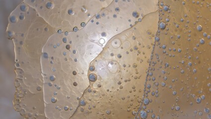 Close up of textured beige and gold abstract pattern with dark speckles