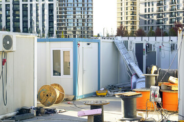 Temporary construction site office with portable containers and scattered equipment near...