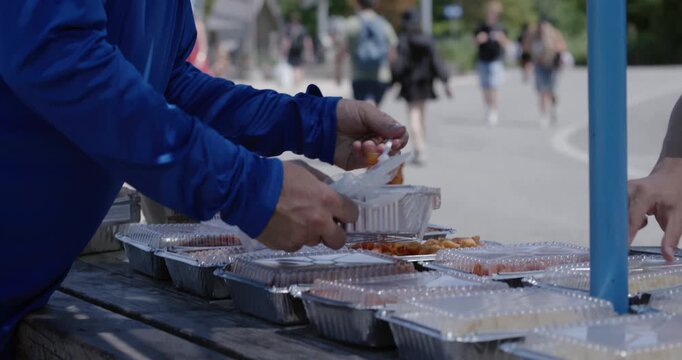 Man in public area putting food on his plate, handheld tilting shot