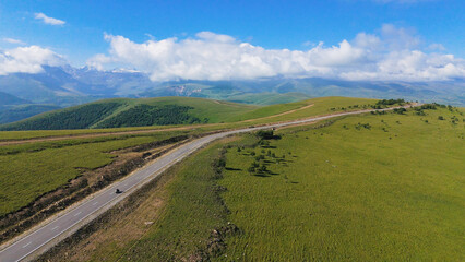 a car is driving along a mountain road in the Caucasus to the Dzhily-su tract, and the peak of Elbrus is visible through the clouds