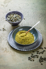 Pumpkin seed flour in a bowl with seeds, healthy food concept