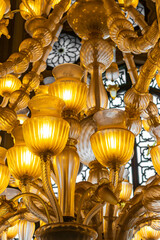 A luxurious gold chandelier with many lamps in the interior of the Hassan II Mosque in Casablanca. Oriental ornaments and soft warm light create an atmosphere of grandeur and spirituality.