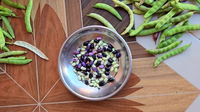 The process involves peeling/snapping the pod open by hand, collecting the inner beans in a plate or bowl, and setting the empty, unusable pod husks aside separately.