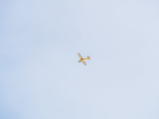 Small ultralight airplane with overhead wing and single propeller flying in sunset sky.