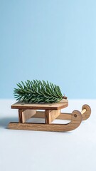 Mini wooden sled with small pine branch on pastel blue background.