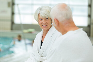 Obraz premium senior couple at indoor pool wearing bathrobes