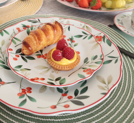 Table setting with bright tableware, berries, and twigs. Dessert on plate. Aesthetics and lifestyle. Home design. 