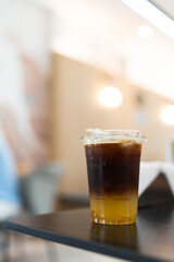 A glass of iced americano black coffee and layer of orange on table