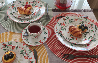 Table setting with bright tableware, berries, and twigs. Dessert on plate. Aesthetics and lifestyle. Home design. 