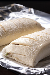 Raw apple strudels, with sliced pastry, on foil ready for cooking in an oven. Home baking concept