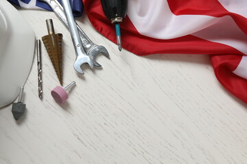 Image of work gloves, tools and American flag on wooden surface symbolizing Labor Day in the USA
