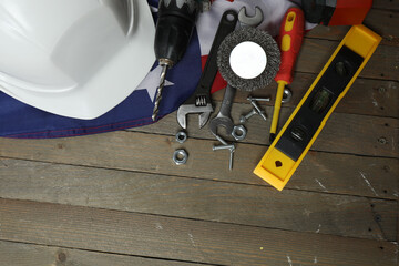 Image of work gloves, tools and American flag on wooden surface symbolizing Labor Day in the USA

