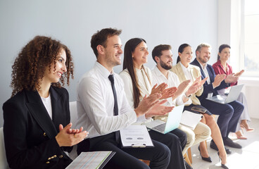 Diverse crowd of happy business people in an office applauding during a meeting or event....