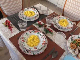 Table setting with bright tableware, berries, and twigs. Saffron risotto on plate. Traditional Italian food. Aesthetics and lifestyle. Interior design. 
