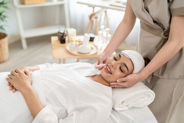 Obraz premium Beautiful woman getting facial massage with gua sha at beauty spa.