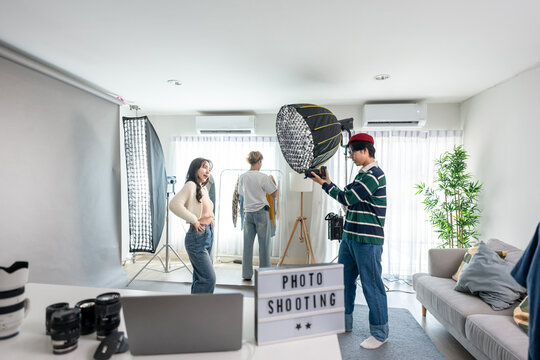 Asian woman model being photographed by cameraman in a photography studio. - Powered by Adobe