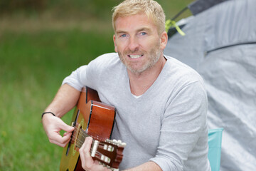 man playing guitar outside the tent