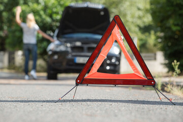 warning triangle with woman hailing help for broken down car