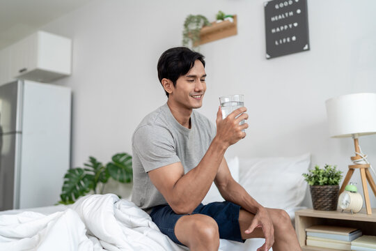 Asian handsome young man drinking a glass of water in the morning.