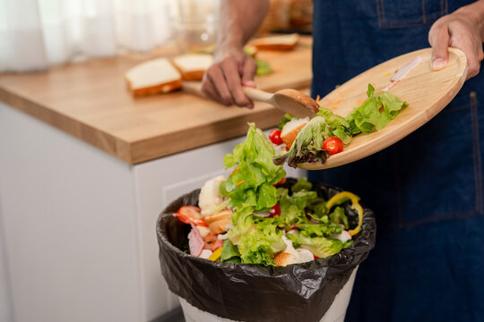 Close up of man throwing away fresh food scraps into trash bin.  - Powered by Adobe