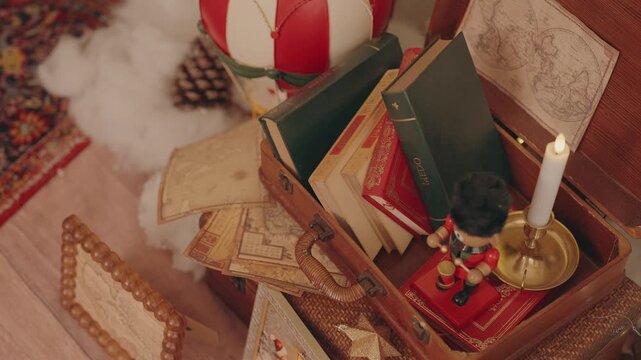 Old suitcase filled with books maps and candle beside festive decor
