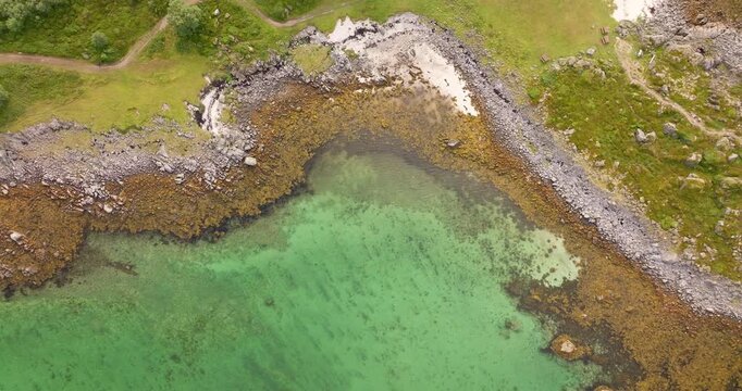 Rocky coastline and clear turquoise water, &Aring;rnessan, Stokmarknes, Norway. Aerial drone top-down ascending