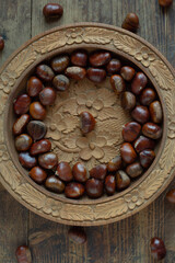Fresh chestnuts on a wooden plate.Vertical shot.