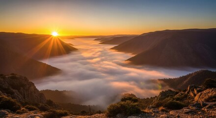 Aerial view of a mountain valley filled with low-lying clouds, lit by a vibrant sunrise