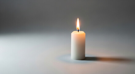 A white wax candle burns brightly against a neutral background, casting a soft glow and gentle shadows, perfect for representing peace, remembrance, or hope.