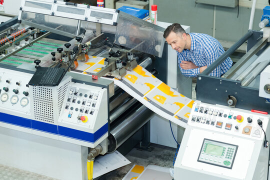 man inspecting industrial printing machine