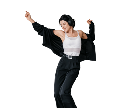 Young hispanic woman in black sweater and pants dancing on couch listening music using headphones smiles enjoys vacations on transparent background
