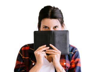 Purposeful brunette woman in plaid shirt hiding behind diary looks at camera on transparent background
