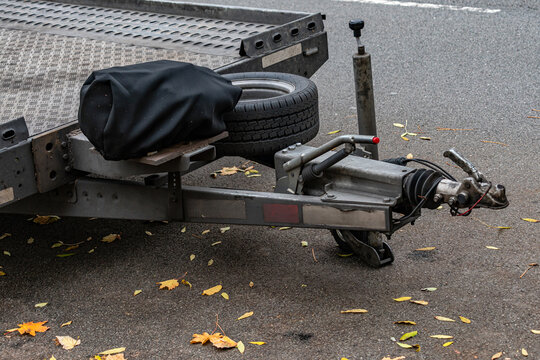 Tow hitch with a black cover near a roadway with fallen leaves
