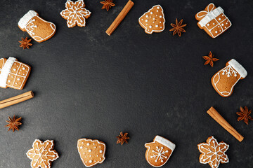 Gingerbread cookies shaped like mittens snowflakes stockings tree gift on dark surface